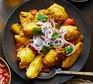 A plate serving chicken curry garnished with red onions