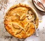 Chicken pot pie in a baking dish with a spoon removed