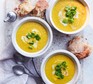 Marrow soup served in three bowls with herb garnish and crusty bread