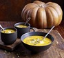 Creamy pumpkin & lentil soup in a black bowl and two mugs