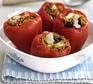 Four stuffed peppers with rice and cheese in a serving dish