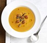 Pumpkin soup in a white bowl, topped with croutons