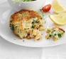 Salmon fish cake on a plate with lemon wedges and salad