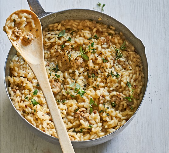 Pot of sausage and fennel risotto with wooden spoon