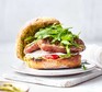 A sausage sandwich with pesto served on a plate