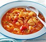 Simple fish and tomato stew in a white bowl with a spoon