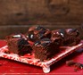 Vegan chocolate brownies with a crushed cookie topping on a serving tray